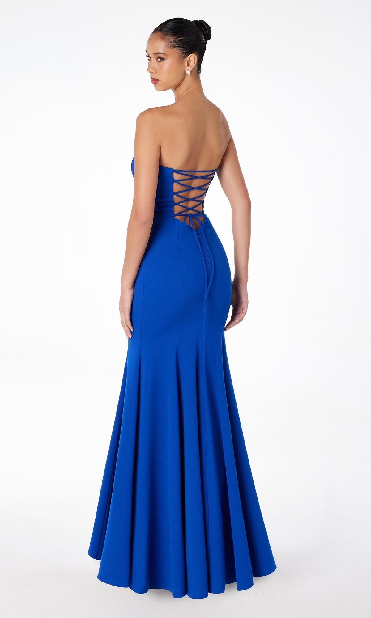 A woman models the Astee T2010 Lace-Up Strapless Long Prom Dress, standing with her back to the camera and glancing over her shoulder.